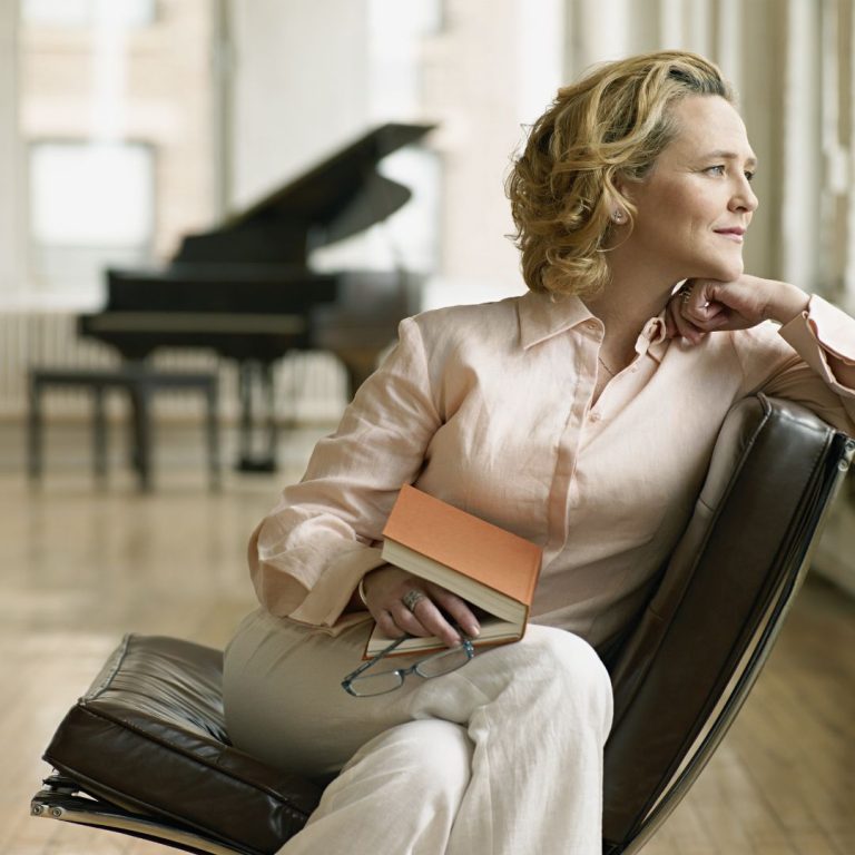 woman looking out window with books in her lap