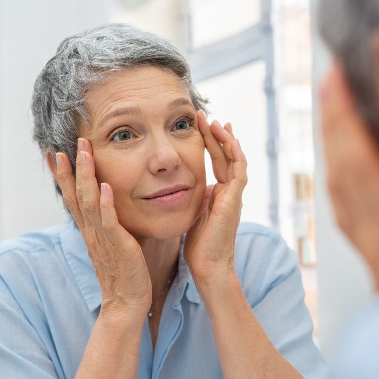 woman looking in mirror at her face